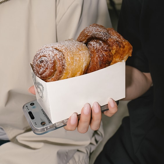 A closeup of hands holding a phone and pastries