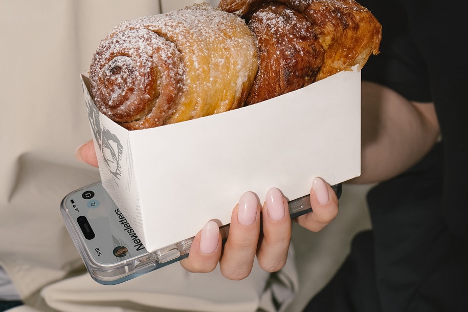 A closeup of hands holding a phone and pastries